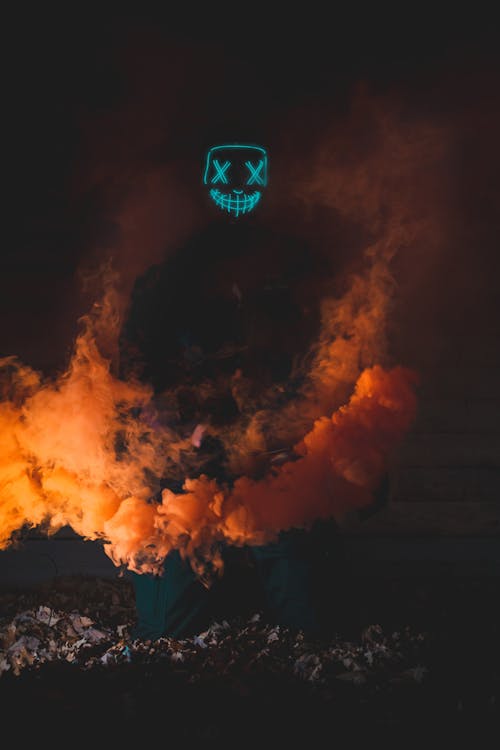 Person Wearing Purge Mask Surrounded with Orange Smoke