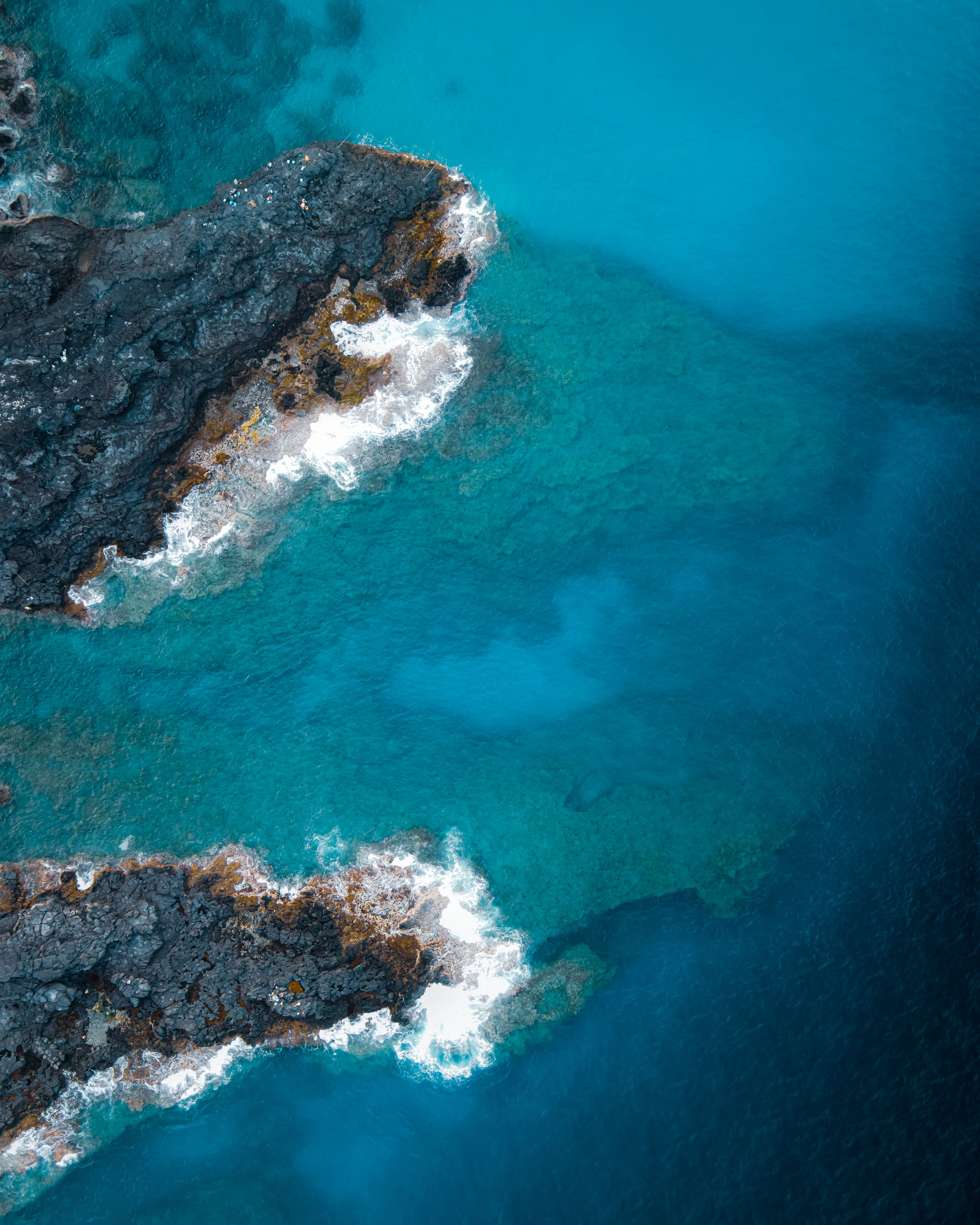 Drone view of seascape with rough stony formations with uneven surface located among azure sea in nature in tropical country