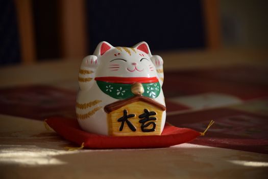 Capture of a Japanese Maneki Neko figurine on a red cushion, symbolizing good fortune.