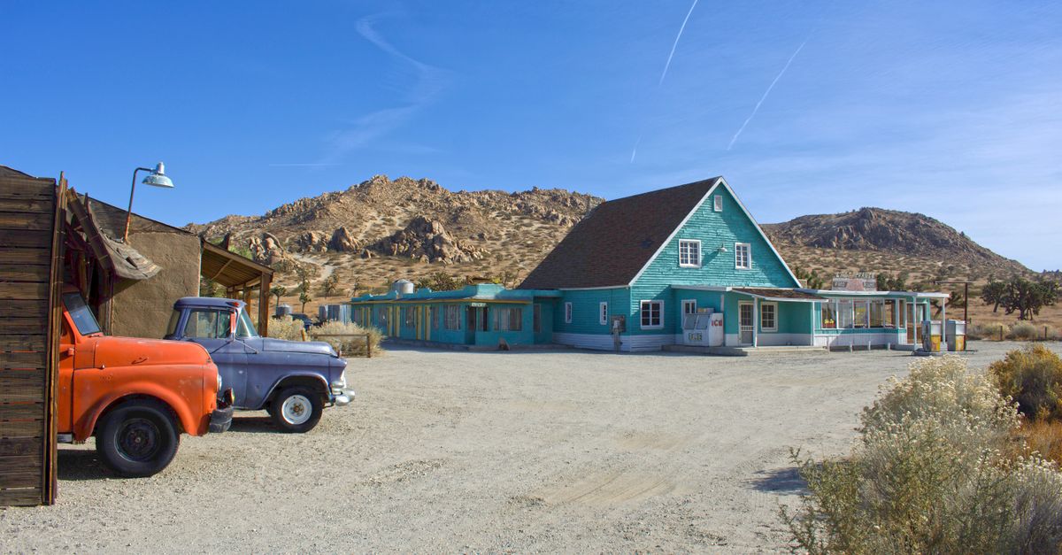 Blue house in a rural, arid landscape with vintage trucks in Lancaster, CA.