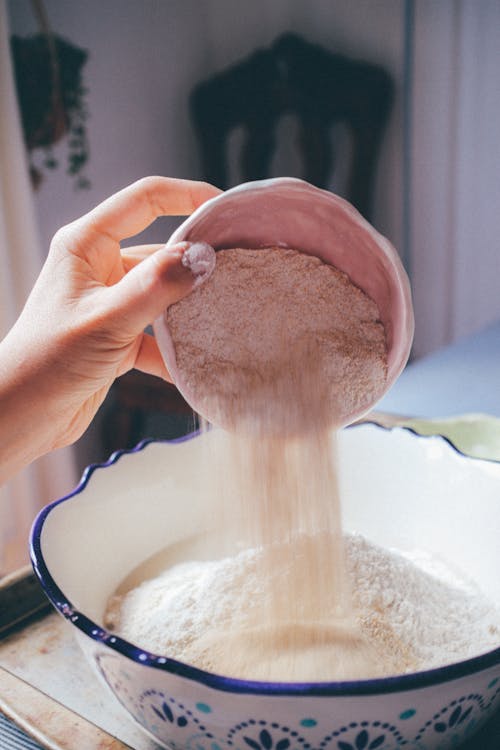 Close-Up Shot of a Person Pouring Flour in a Bowl