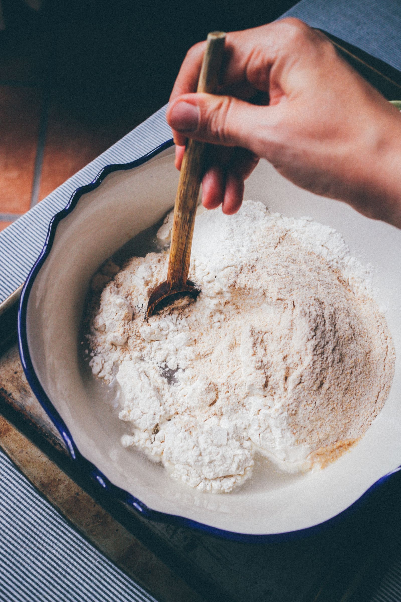 Bowl of flour with a wooden spoon on a kitchen surface