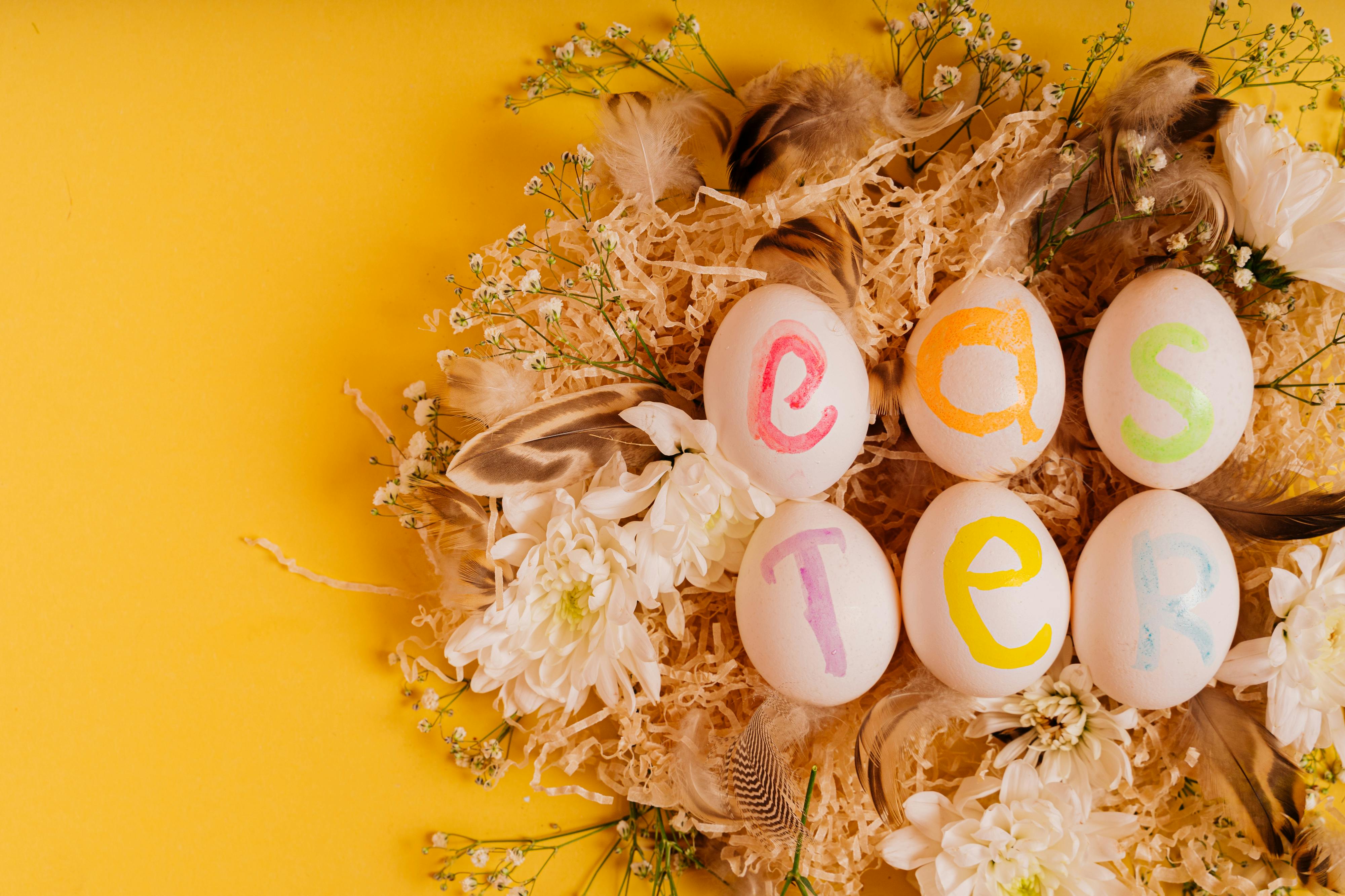 Vibrant Easter eggs with colorful letters and floral decoration on a yellow background.