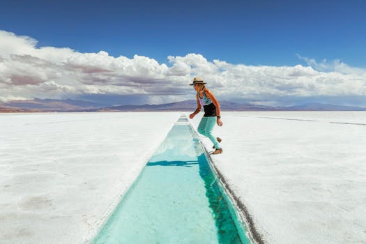 Woman exploring Salinas Grandes salt flats under a bright sky, showcasing adventure and nature.