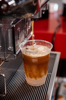 Close-up of iced coffee being prepared with an espresso machine, showcasing creamy textures.