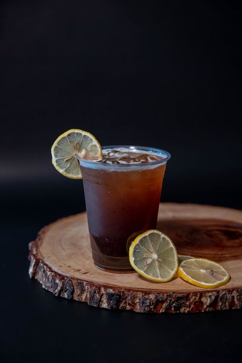 Free Refreshing iced tea with lemon slices on a wooden slab against a dark background. Stock Photo