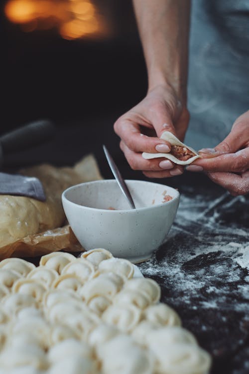 A Person Holding a Dumpling Dough with Filling