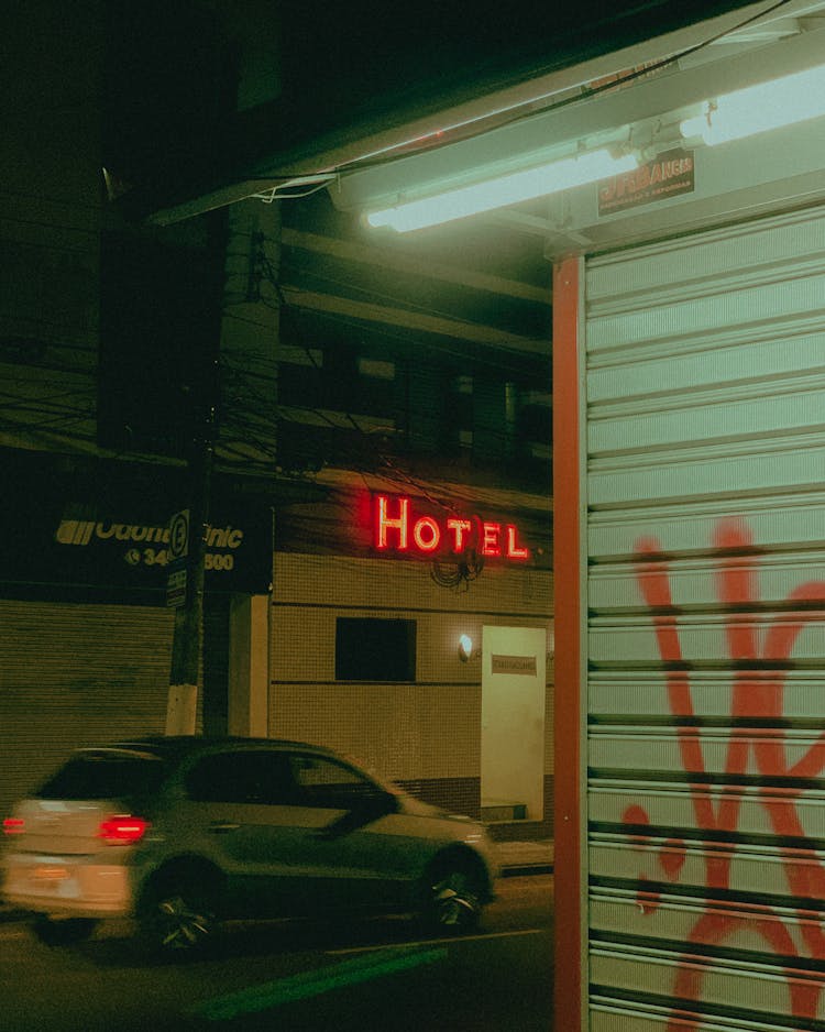 
A Car Driving On A Road In Front Of A Hotel