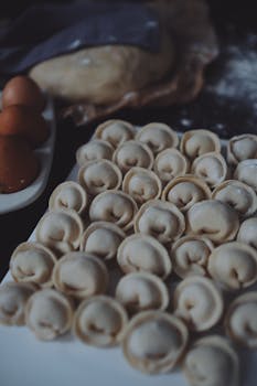 A collection of fresh homemade dumplings on a ceramic plate ready for cooking.