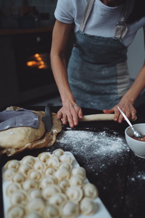 Free Person preparing homemade dumplings with dough and filling in a cozy kitchen. Stock Photo