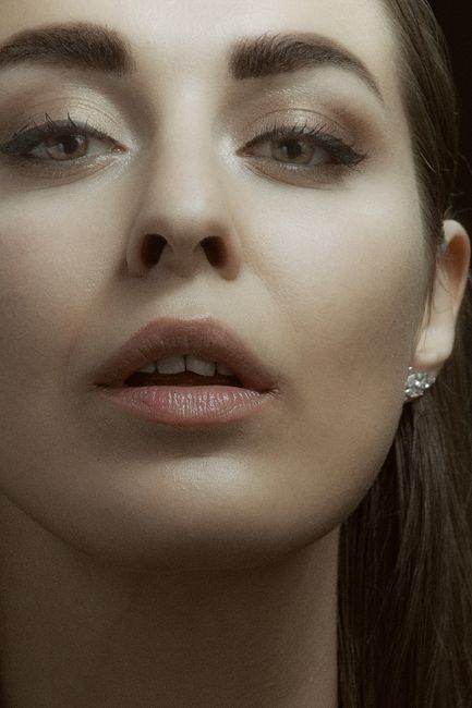 Close-up portrait of a woman with makeup, highlighting facial features and elegance.