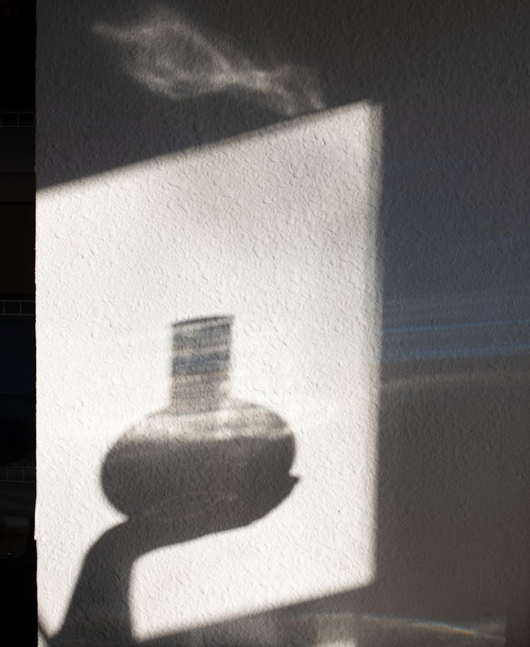 Shadow Of Crop Person With Liquid In Bottle