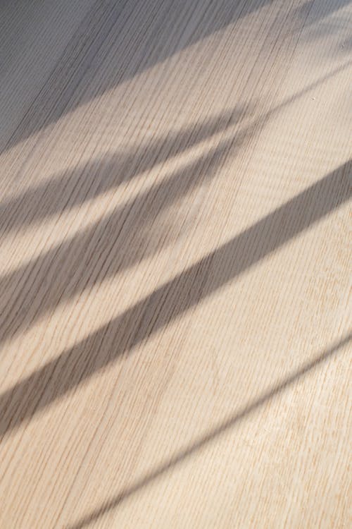 From above of curtain shadow on wooden floor in room on sunny day