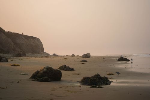 Free A tranquil beach scene at sunset with rock formations and gentle waves creating a peaceful atmosphere. Stock Photo