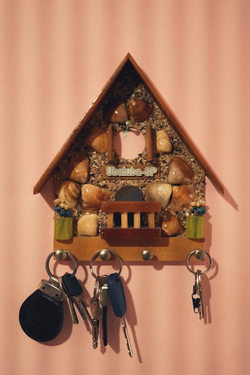 Timber decorative retro house with seashells and hanging keys on pink wall with stripes