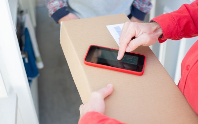 A courier scanning a parcel with a phone