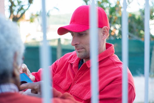 A delivery worker in a red cap and jacket interacts outside, featuring a casual yet focused look.