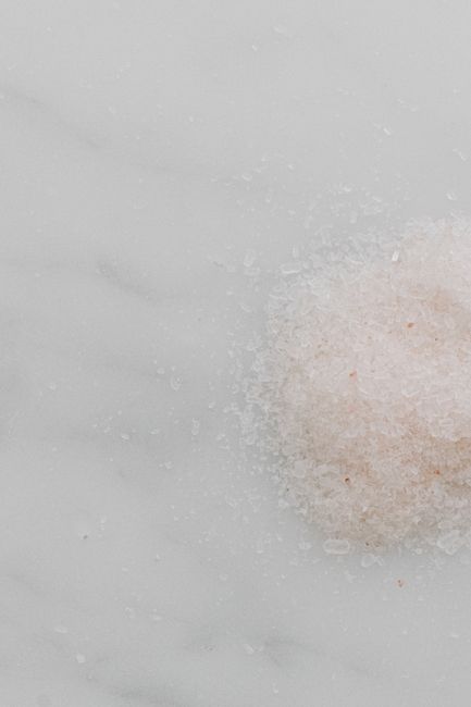 Fotomural Toma estética en primer plano de sal de baño rosa del Himalaya sobre un fondo limpio de mármol blanco para fines de spa o bienestar.