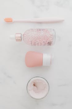 Flat lay of skincare products on a marble surface, featuring soft pastel tones.