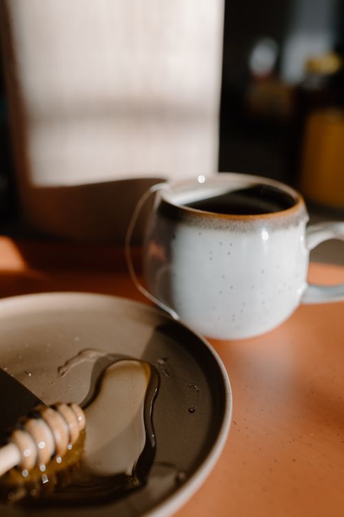 Free Warm beverage setting with honey dipper and ceramic mug, perfect for a cozy afternoon. Stock Photo