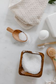 Top view of organic bath essentials including bath salt and brushes on a light background.
