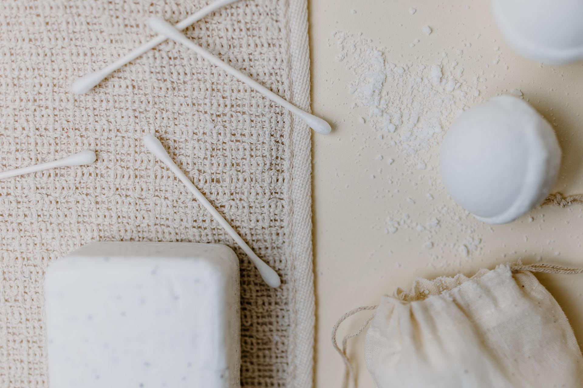 Top View of Cotton Swabs, Bath Bombs and a Bar of Soap Lying on a Cloth