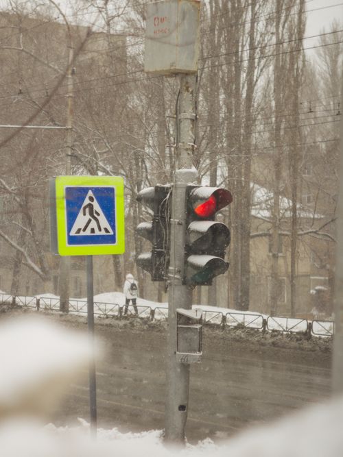 Free Winter scene with a snow-covered traffic light and pedestrian crossing sign on a quiet urban street. Stock Photo