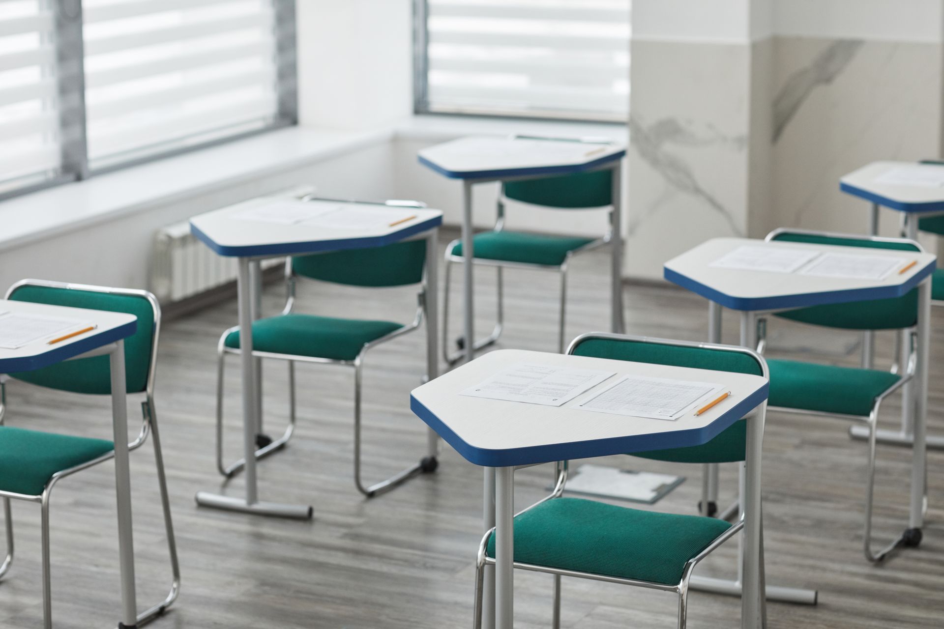 An empty classroom with arranged desks and exam papers ready for students