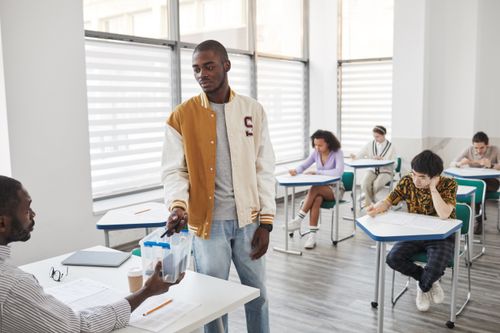 Free Group of students taking exams in a modern classroom setting. Stock Photo