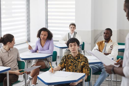 Students engaging in a college classroom, taking notes and participating actively in discussions.