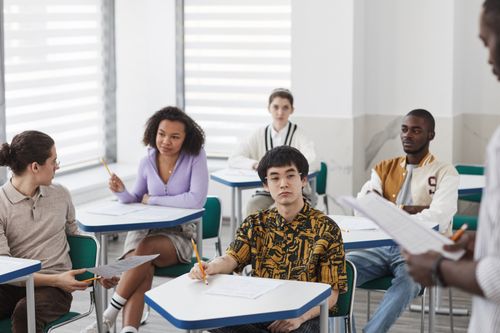 Free Students engaging in a college classroom, taking notes and participating actively in discussions. Stock Photo