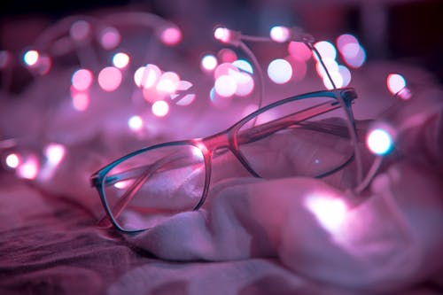 Shallow Focus Photography of Blue-framed Eyeglasses Near String Lights