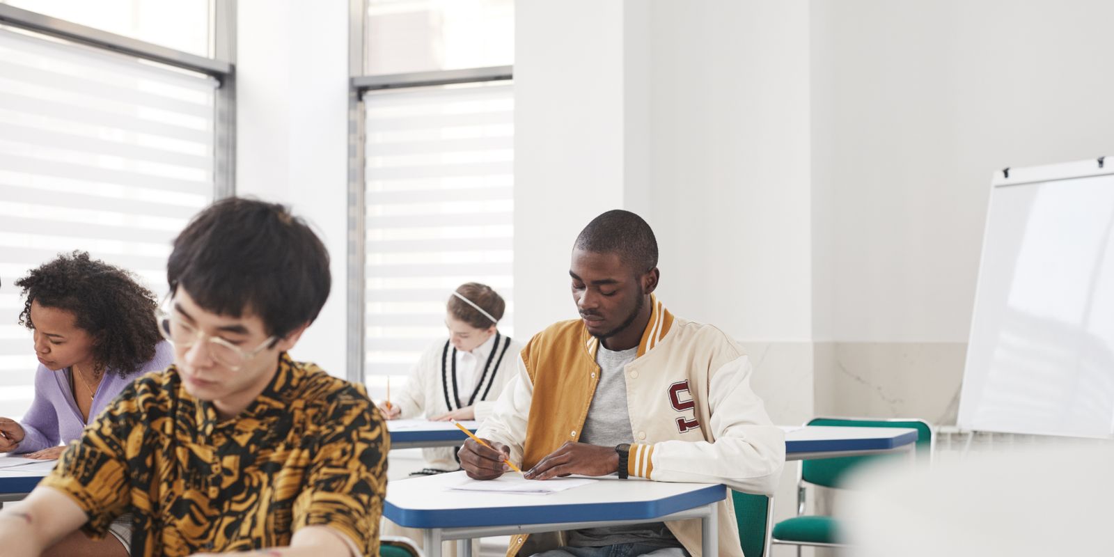 Focused college students in a classroom taking an exam, showcasing diversity and collaboration.
