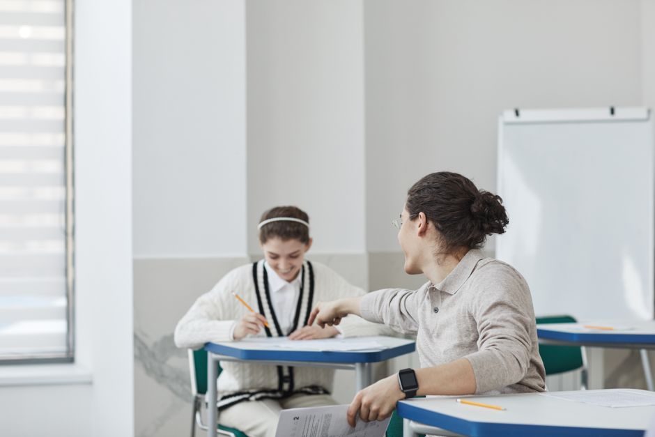 Two students collaborate during an exam in a classroom setting.