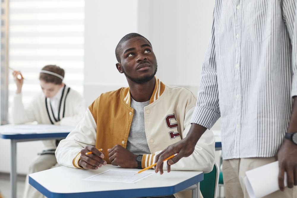 Un jeune attentif en classe, un adulte à ses côtés