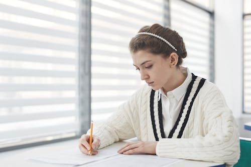 Woman in a White Knitted Sweater Taking an Exam