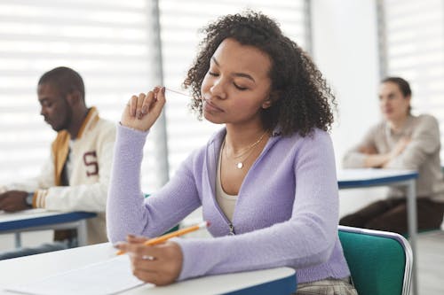 Free Close-Up Photo of a Woman in a Purple Cardigan Sweater Taking an Exam Stock Photo