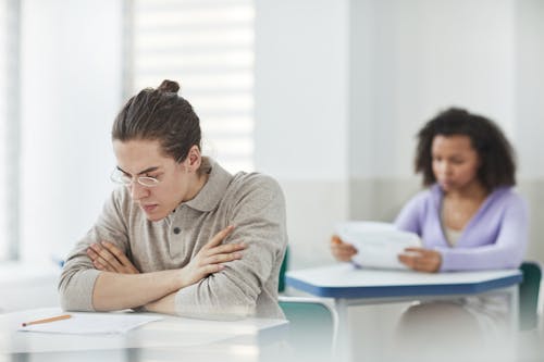 Selective Focus Photo of a Man with Eyeglasses Looking at His Test Paper