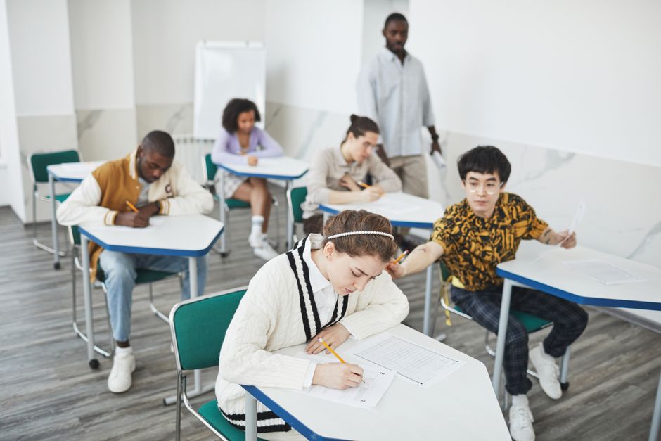 Students focused on a standardized test in a bright, clean classroom - Clean school environment Students focused on a standardized test in a bright, clean classroom - Clean school environment