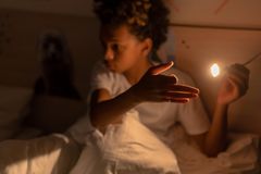 A young boy engaging with a light source in a dimly lit bedroom, creating a playful atmosphere.