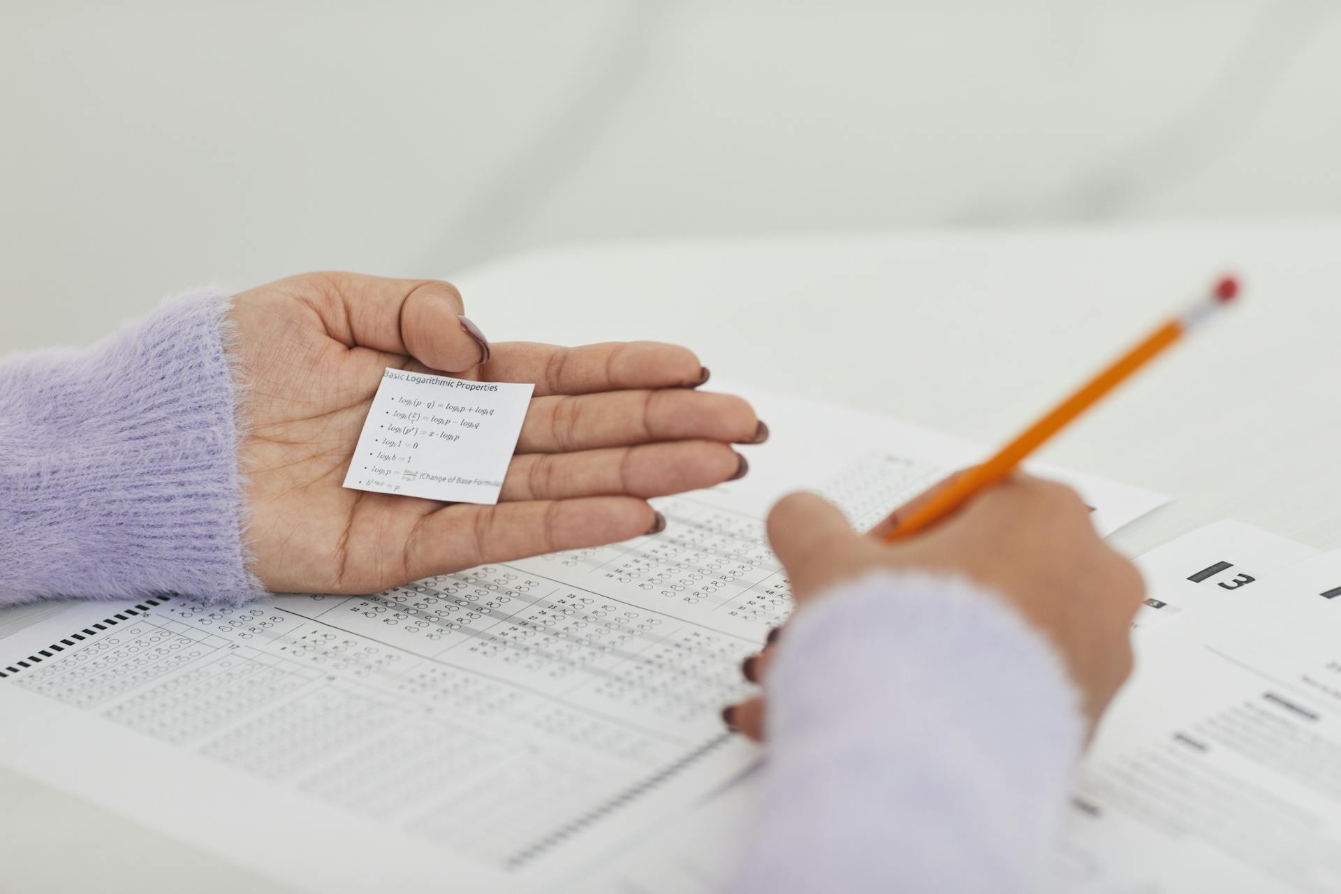 Close-up of a student using a cheat sheet during an exam, highlighting academic dishonesty.