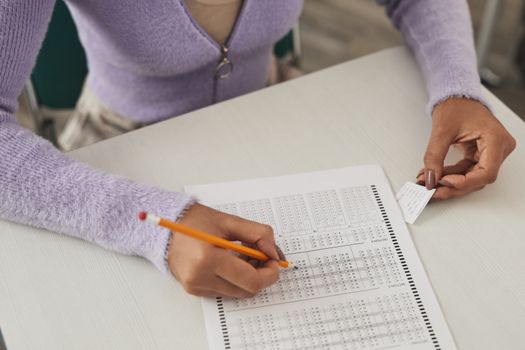Close-up of a person using a cheat sheet while answering a multiple-choice exam.