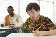 A Man Handing Over a Cheat Sheet on His Classmate