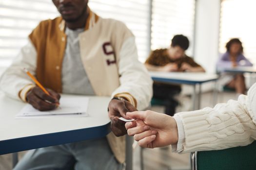 Students discreetly exchange paper during a test in a classroom setting.