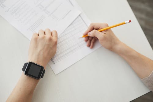 A Person Wearing a Smart Watch while Holding a Pencil