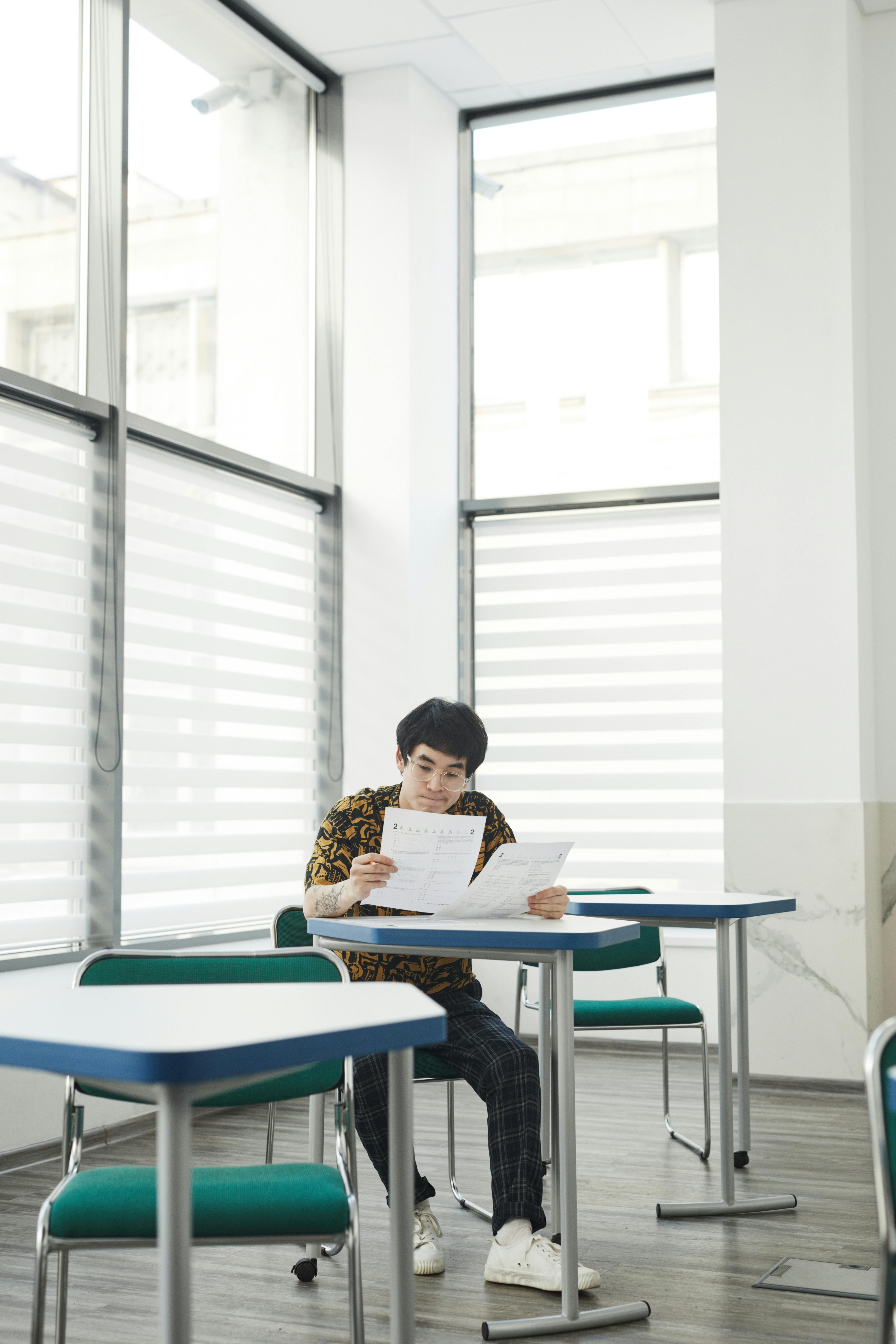 An adult student concentrating on a test in a well-lit classroom environment.