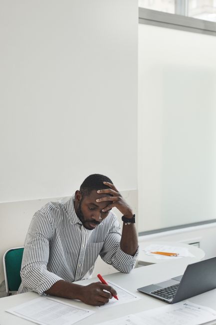 Businessman working on documents with a laptop, pensive and focused. Writing A Formal Undergraduate Research: page requirements.