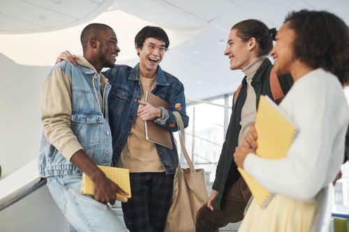 Free A diverse group of young adults laughing and socializing inside a modern building. Stock Photo