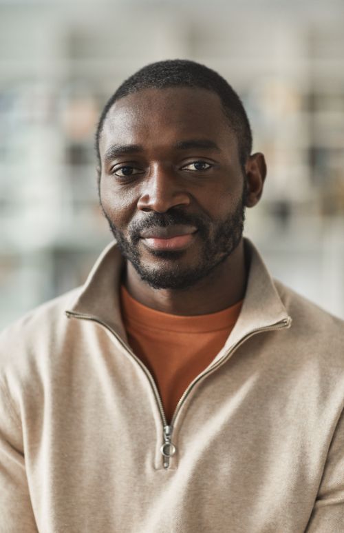 Free Portrait of a smiling man with facial hair in a beige jacket indoors. Stock Photo