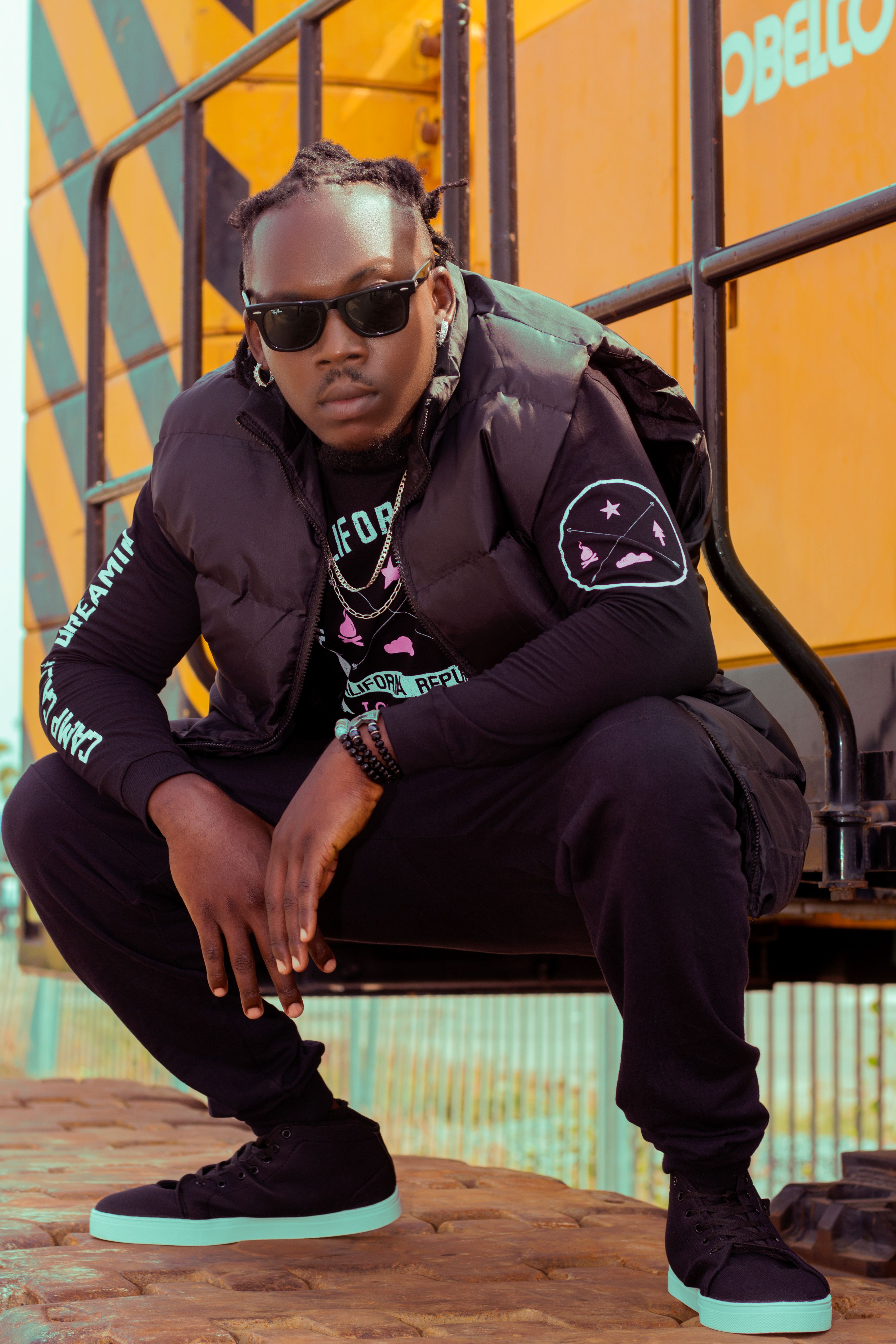 Stylish man in urban streetwear with sunglasses posing outdoors for fashion vibes.